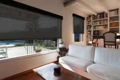 a living room with a white couch and book shelf filled with books next to a window