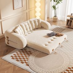 a large white couch sitting on top of a rug in a living room next to a potted plant