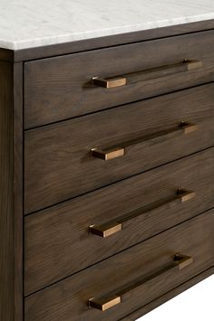 a wooden dresser with marble top and brass pulls on the bottom drawer, against a white background