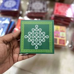 a hand holding up a green sticker in front of some other colored boxes on the table