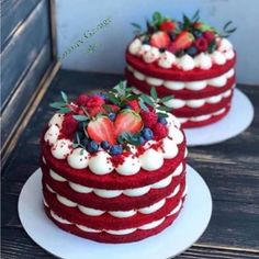 two red velvet cakes with white frosting and strawberries on top