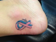 a tattoo on the foot of a person with a pink and blue ribbon around it