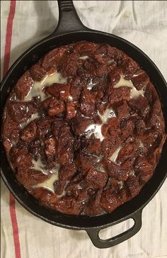 a skillet with some food in it sitting on a table next to a red and white towel