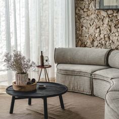 a living room filled with furniture and a stone wall behind the couch is a round coffee table