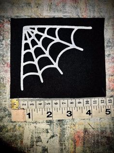 a spider web on black fabric with measuring tape