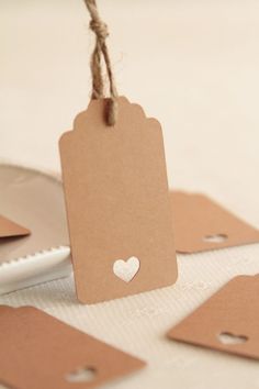 some tags are hanging from twine on top of each other with a heart in the middle