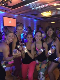 a group of women standing next to each other holding cans in their hands and posing for the camera