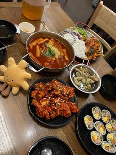 a table topped with plates of food next to a stuffed animal and cupcakes