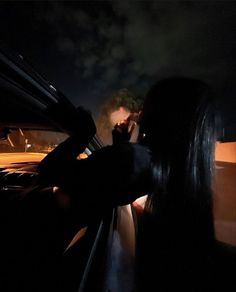 a man and woman sitting in a car at night