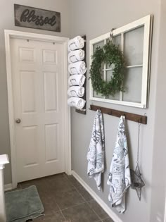 towels are hanging on the wall in front of a door with wreaths and window