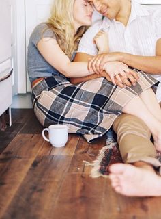 a man and woman sitting on the floor next to each other with their arms around each other