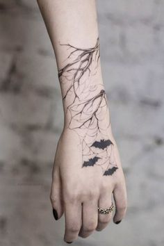 a woman's hand with a tattoo on it and bats flying around the wrist