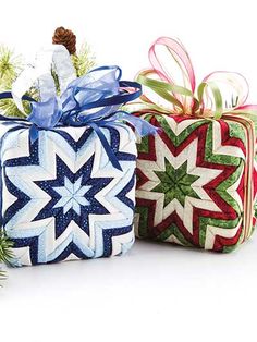 three wrapped presents sitting next to each other on top of a white surface with pine branches