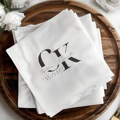 four napkins on top of a wooden plate with white flowers in the background and gold cutlery