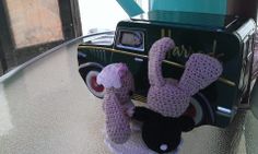 a crocheted stuffed animal hanging from the handle of an old toy car with its hands in the air