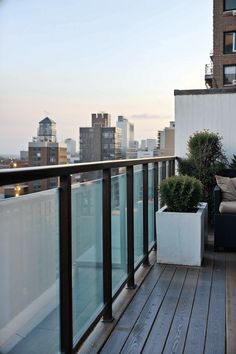 a balcony with a couch and potted plants on the outside, looking out over the city