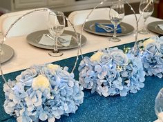 the table is set with blue flowers and silverware