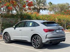 an audi suv parked in a parking lot with red flowers behind it and a sale sign on the rear window