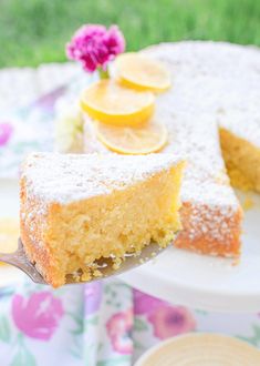 a piece of cake on a plate with a fork and flowers in the back ground