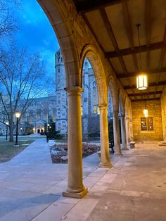 an empty walkway with columns and lights at night