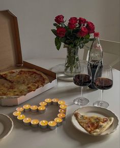 a table topped with two pizzas and glasses of wine next to candlelight candles