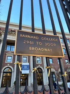 the entrance to barnard college is adorned with gold ribbon and bowes as it stands behind an iron gate