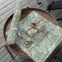 a wooden table topped with a map wrapped in wrapping paper next to a pair of scissors