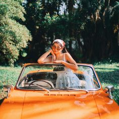 a woman sitting in the driver's seat of an orange car