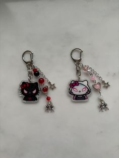 two hello kitty keychains with charms attached to them on a marble surface in front of a white background