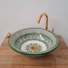 a green and white bowl sink sitting on top of a wooden counter next to a faucet