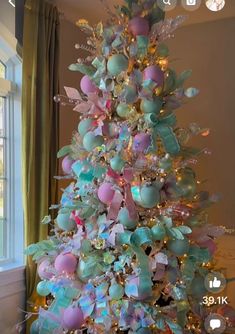 a decorated christmas tree with pastel blue, pink and green ornaments on it's branches