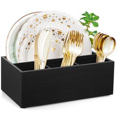 a black tray with gold and white plates, silverware and a green sprig