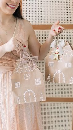 a woman in a dress holding two bags with houses on them and a star hanging from the top