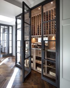 an open wine cellar with glass doors leading into the kitchen and dining room area is shown