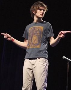 a young man standing on top of a stage holding his hands out in front of him