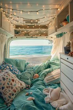 the inside of a camper van with lights strung from the ceiling and seashells on the bed