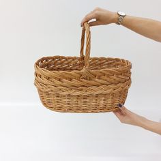 two hands holding a wicker basket on a white background with the handle extended up