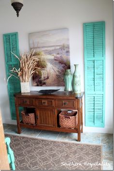 there is a wooden table with baskets on it in front of green shuttered doors