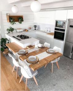 a kitchen with a table, stove and refrigerator in the center is seen from across the room