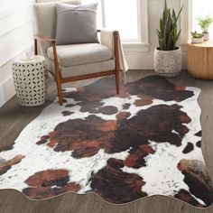 a cowhide rug with brown and white spots on the floor next to a chair