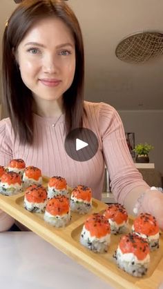 a woman holding a tray with sushi on it