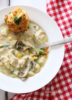 a white bowl filled with chicken and dumpling soup on top of a checkered table cloth