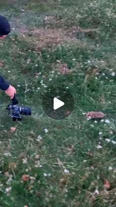 a person kneeling down in the grass with a camera