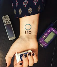 a woman's hand with a small tattoo on her wrist next to an electronic device