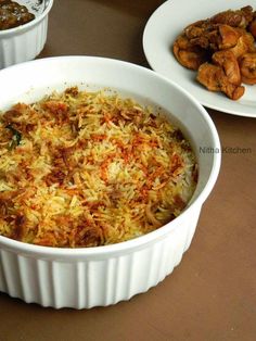 two white dishes filled with food on top of a table