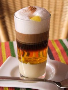 a glass filled with liquid sitting on top of a white plate