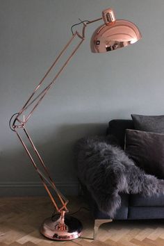 a floor lamp sitting on top of a wooden floor next to a gray couch in a living room