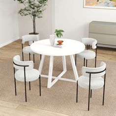 a white table with four chairs and a potted plant in the corner next to it