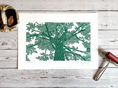 a green and white tree print sitting on top of a wooden table next to a pair of scissors