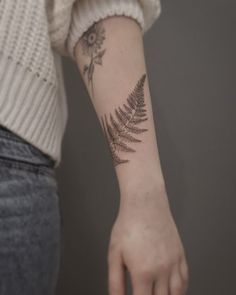 a fern leaf tattoo on the left arm